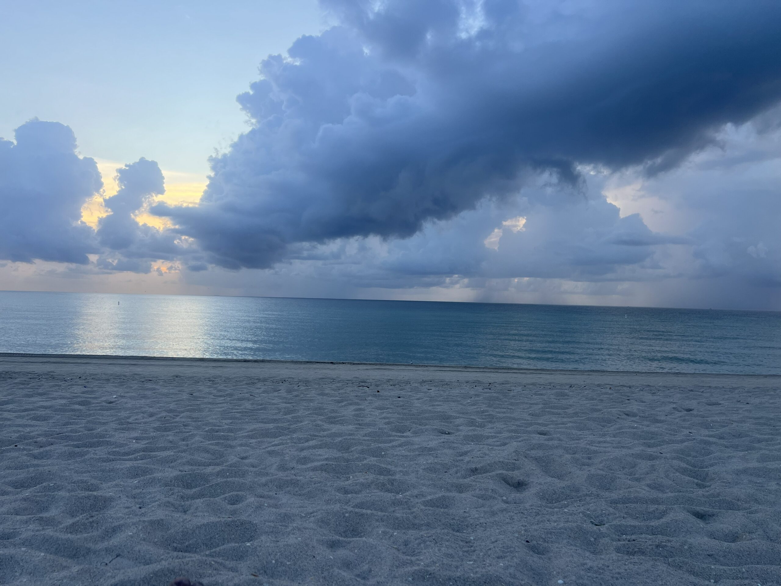 Serene beach view at dusk, showcasing calm waters and clouds