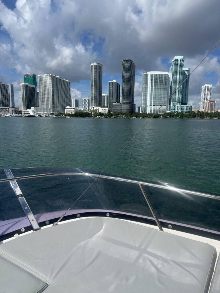 Modern skyscrapers line the Miami waterfront, viewed from the bow of a boat