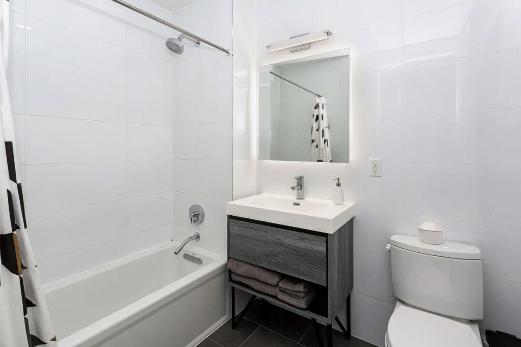 Modern bathroom featuring a tub with shower, sleek vanity, and minimalist decor