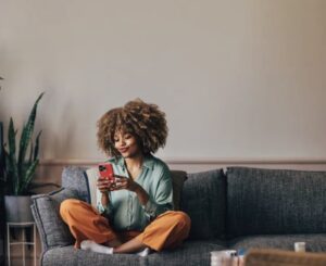 A woman with curly hair sits on a grey sofa