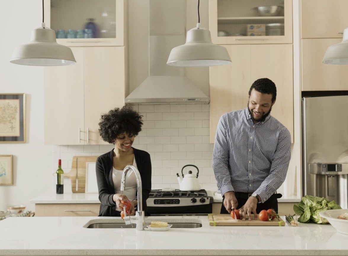 A smiling couple prepares a meal together