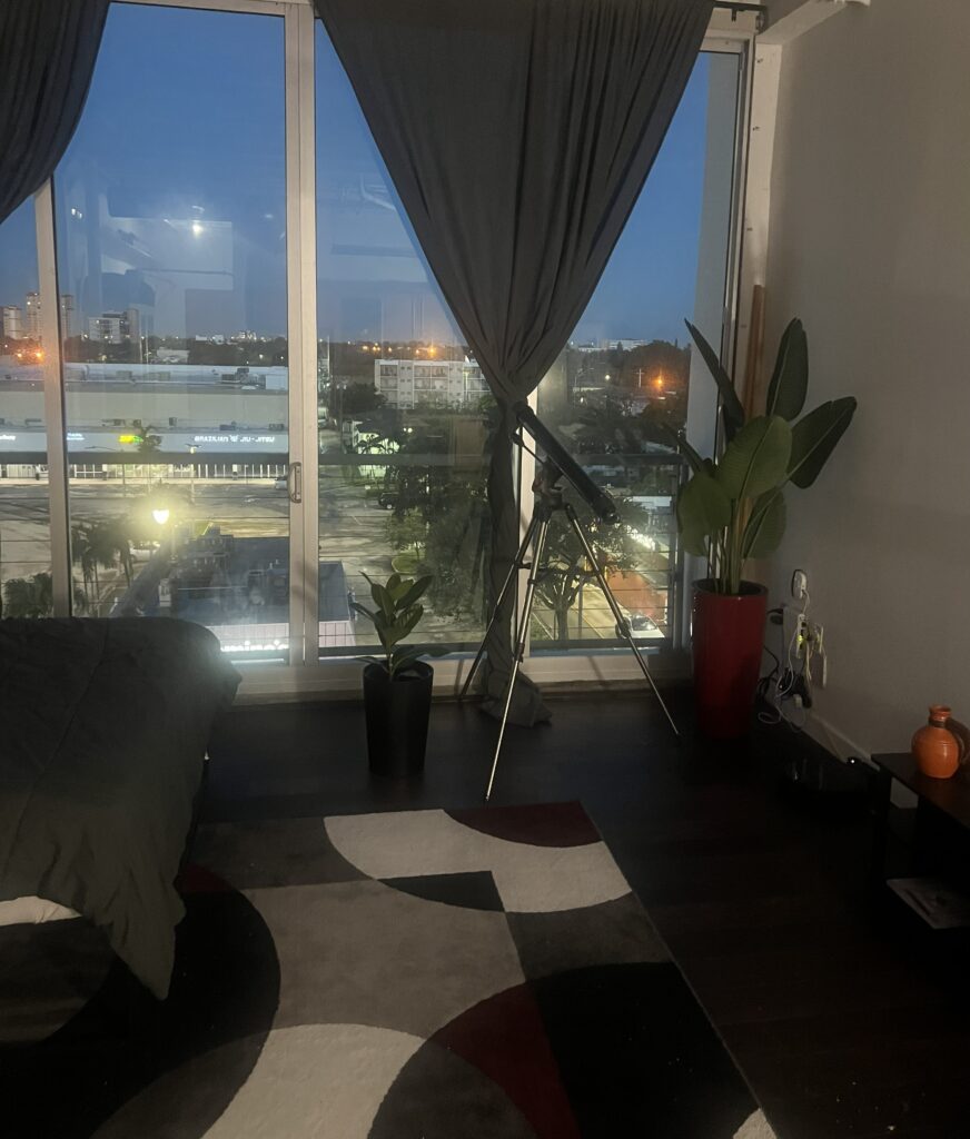Cozy room with dark curtains, a telescope by the window