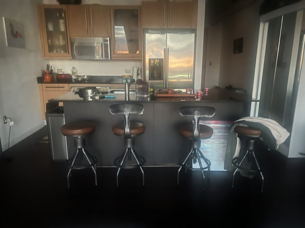 Modern kitchen featuring a central island with four metal bar stools